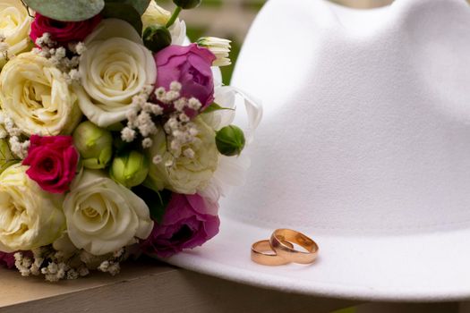 wedding rings on a white stylish hat next to the bride's bouquet. marriage concept.