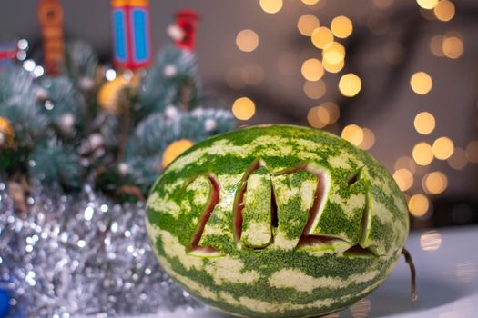 watermelon with 2021 carved number next to new year decorations. christmas theme.