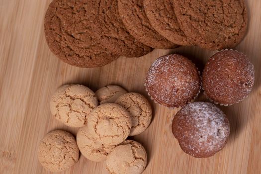 muffins, almond amaretti and oat cookies on wooden stand board. concept of sweet bakery