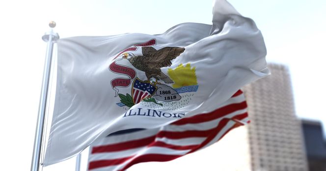 The Illinois state flag flapping in the wind with the American national flag blurred in the background. Democracy and independence. American midwest state.