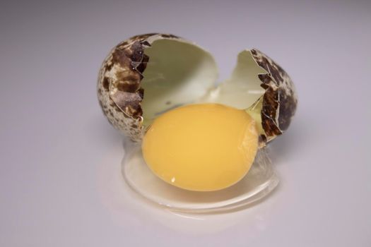 broken Quail egg isolated on white background with leaking white and yolk. healthy raw food.