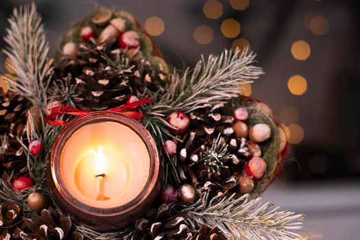 Christmas decor star-shaped made of tree branch with new years toys on it and a candle in it.