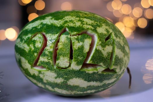 watermelon with 2021 carved number next to new year decorations. christmas theme.