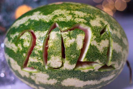 watermelon with 2021 carved number next to new year decorations. christmas theme.