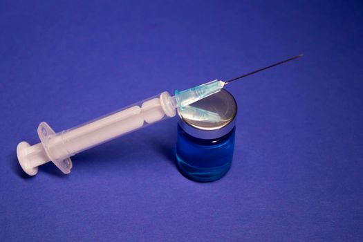 Vaccine bottle phial with no label, medical syringe injection needle. isolated on blue background. Development of coronavirus vaccine COVID-19. cure. World race in researching. copy space