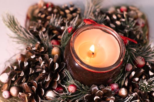 Christmas decor star-shaped made of tree branch with new years toys on it and a candle in it.