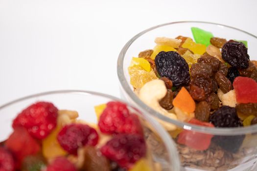 muesli dessert with yogurt and candied or dried fruits with raspberries on top in glass isolated on white background. breakfast Granola