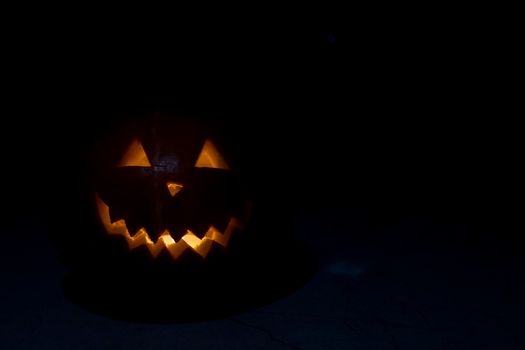 Halloween pumpkin in the dark with lighted candle inside. horror theme and Hallowe'en.