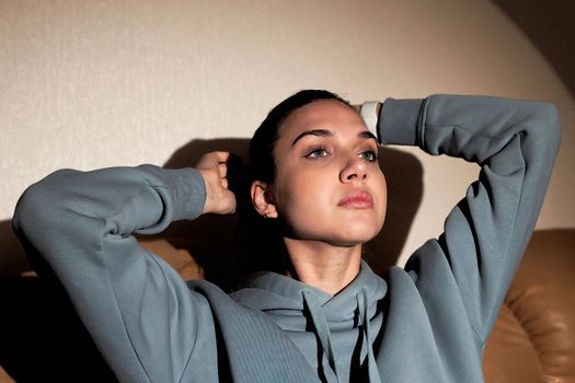 Portrait of a cute brunette woman holding hands behind her head. Close up