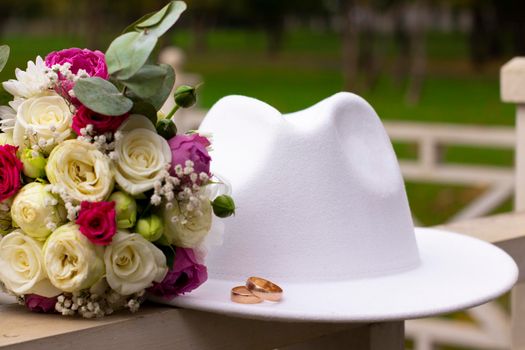 wedding rings on a white stylish hat next to the bride's bouquet. marriage concept.