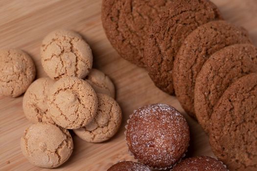 muffins, almond amaretti and oat cookies on wooden stand board. concept of sweet bakery