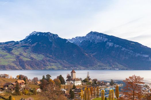 Stunning panorama view of Spiez town and Lake Thun with Swiss Alps Sigriswiler Rothorn and  Niederhorn in background on a sunny autumn day with golden. tree, Bernese Oberland, Switzerland