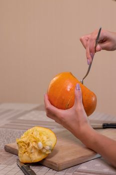 the process of making a Halloween pumpkin. cleansing of seeds by a brunette girl. horror theme and Hallowe'en.