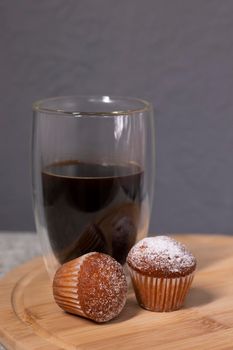 coffee in a double bottom glass near two little cupcakes. coffee break. breakfast.