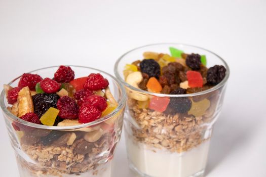 muesli dessert with yogurt and candied or dried fruits with raspberries on top in glass isolated on white background. breakfast Granola