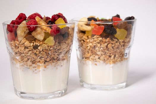 muesli dessert with yogurt and candied or dried fruits with raspberries on top in glass isolated on white background. breakfast Granola