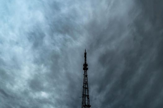 A television or radio broadcasting antenna against a dramatic overcast sky.A cloudy sky with thick rain clouds and a telephone antenna.Communications and telecommunications.Connect and wireless media