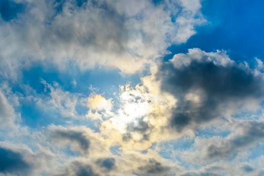 The rays of the sun break through the clouds.Blue sky with white feather clouds. Panoramic view of the blue sky with clouds in motion.Nice weather with clear skies. Panorama of the sky in motion