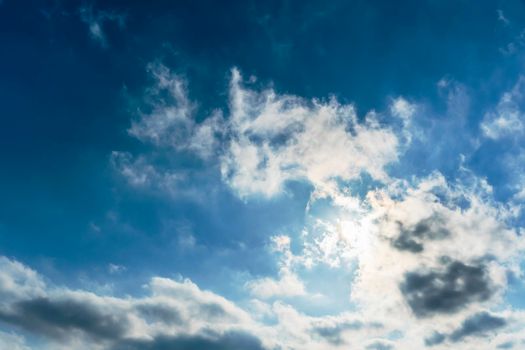 The rays of the sun break through the clouds.Blue sky with white feather clouds. Panoramic view of the blue sky with clouds in motion.Nice weather with clear skies. Panorama of the sky in motion