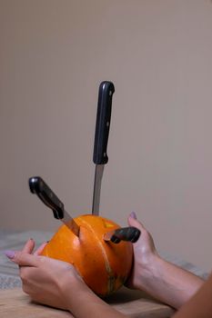 the process of making a Halloween pumpkin. knives stuck in a pumpkin. horror theme and Hallowe'en.