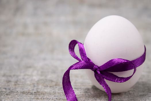 chicken egg wrapped in purple bow-knot. healthy raw food. easter egg, present.