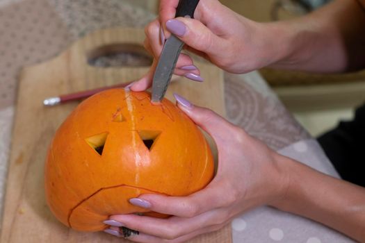 the process of making a Halloween pumpkin. cutting out the mouth. horror theme and Hallowe'en.