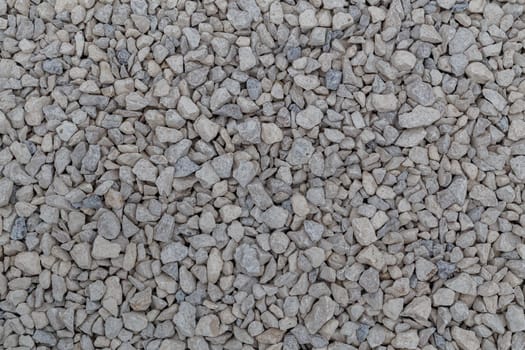 Dry white limestone ballast flat full frame background. Small gray dusty broken macadam stones texture. Viiew from above.