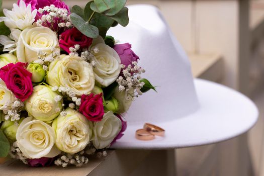 wedding rings on a white stylish hat next to the bride's bouquet. marriage concept.