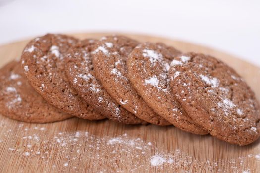 oatmeal cookies covered in powdered sugar on wooden stand board. concept of sweet bakery