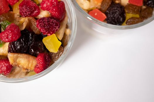 muesli dessert with yogurt and candied or dried fruits with raspberries on top in glass isolated on white background. breakfast Granola