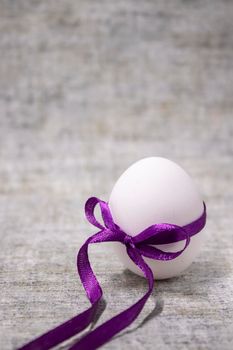 chicken egg wrapped in purple bow-knot. healthy raw food. easter egg, present.