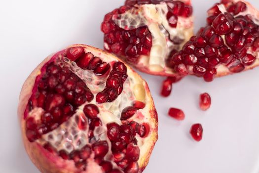 ripe fresh sliced pomegranate fruit with red seeds isolated on white background