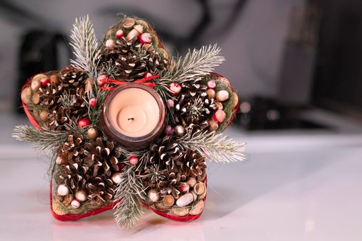 Christmas decor star-shaped made of tree branch with new years toys on it and a candle in it.