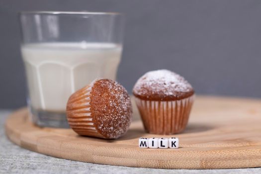 two little cupcakes or muffins in powdered sugar near a glass of milk. healthy breakfast. snack or lunch.