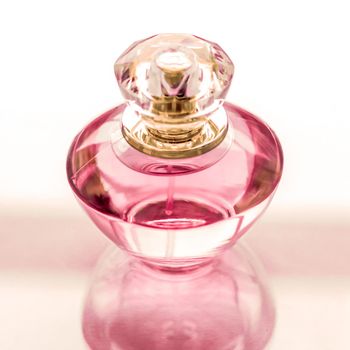 Perfumery, spa and branding concept - Pink perfume bottle on glossy background, sweet floral scent, glamour fragrance and eau de parfum as holiday gift and luxury beauty cosmetics brand design