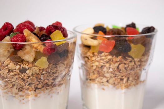 muesli dessert with yogurt and candied or dried fruits with raspberries on top in glass isolated on white background. breakfast Granola