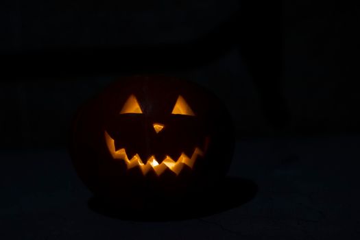 Halloween pumpkin in the dark with lighted candle inside. horror theme and Hallowe'en.