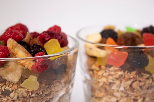 muesli dessert with yogurt and candied or dried fruits with raspberries on top in glass isolated on white background. breakfast Granola