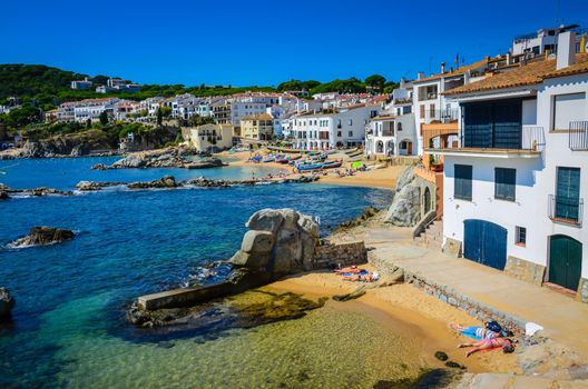 Tourists Sunbathing on beach lining Costa Brava coastline in Girona, Spain.