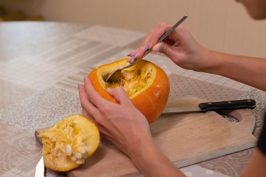 the process of making a Halloween pumpkin. cleansing of seeds by a brunette girl. horror theme and Hallowe'en.