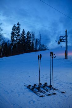 Skis on snowy evening ski slope