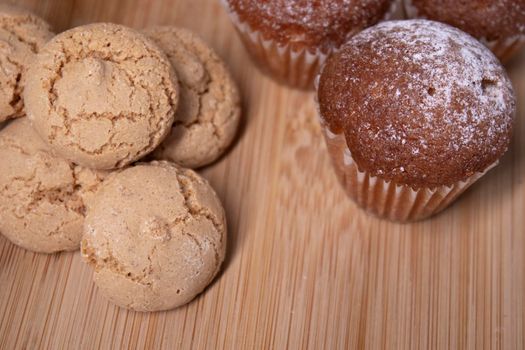 muffins, almond amaretti and oat cookies on wooden stand board. concept of sweet bakery