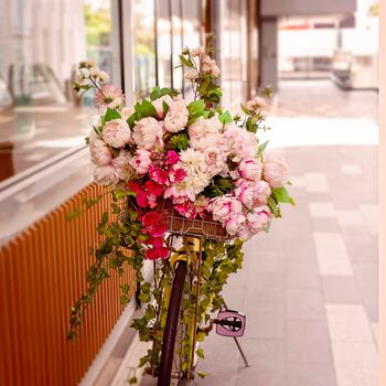 Pink artificial flowers cascading from yellow bicycle handlebars outside a shop
