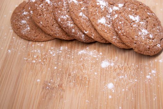 oatmeal cookies covered in powdered sugar on wooden stand board. concept of sweet bakery