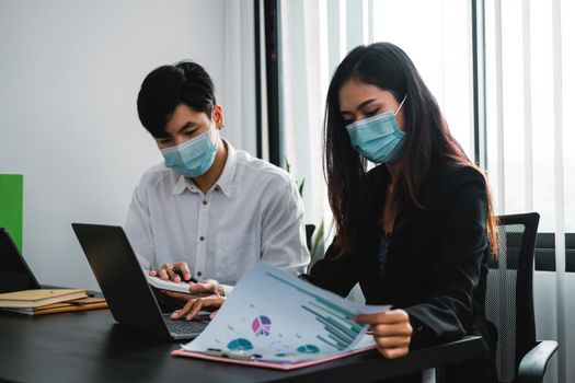 Asian business people have a meeting and working in office and wear mask as protection from corona virus