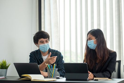 Asian business people have a meeting and working in office and wear mask as protection from corona virus