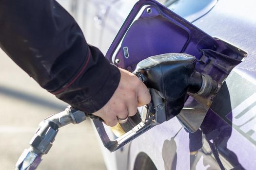 Man holding gas pump filling up car with gas close up . High quality photo