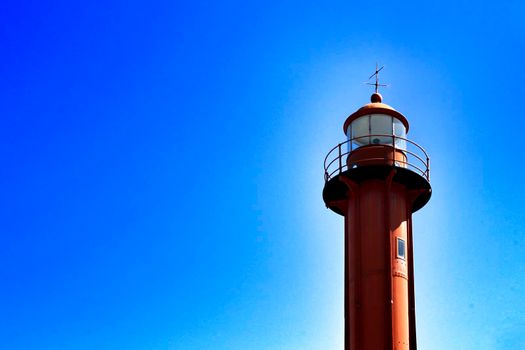 Red lighthouse in the port of Almada village in Lisbon on a sunny day of winter.
