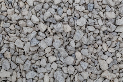 Dry white limestone ballast flat full frame background. Small gray dusty broken macadam stones texture. Viiew from above.