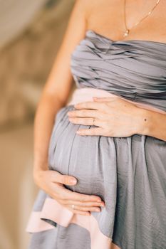 Her hands on pregnant belly. Studio photoshoot birth abortion